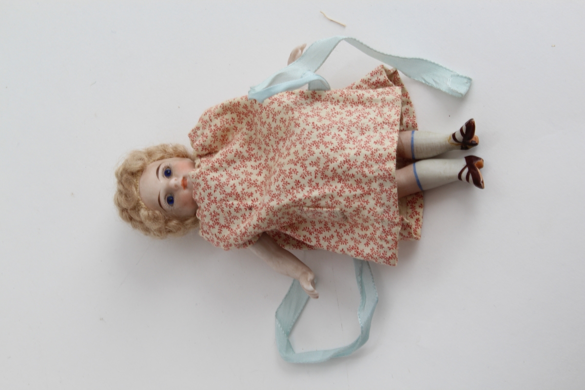 Ganske sikker giver: Karen Collett (f.1921)
To stykk små porselensdukker. Ene med kort krøllete hår, rød blomstrerte kjole med blått silkebånd og påmalt ansikt og sko. Den andre med langt lyst hår i brunprikkete kjole med blått silkebånd og påmalt ansikt og sko.