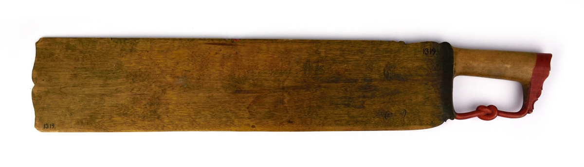 Skäktkniv av trä. På ena sidan av bladet finns blomsterornering i rött, vitt och grönt samt med bläck skrivna verser. Den andra sidan är omålad. På handtagets nederdel finns en snidad knut.