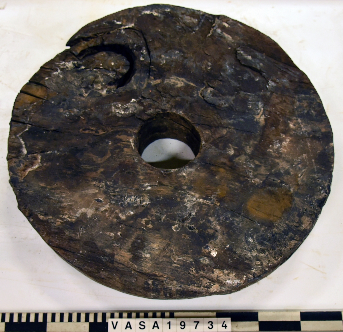 Lavetthjul fram, svåra skador och förorenad yta. Har avfasade kanter.

Front truck of a gun carriage, heavy damage and multiple impurities. Both bevelled edges.