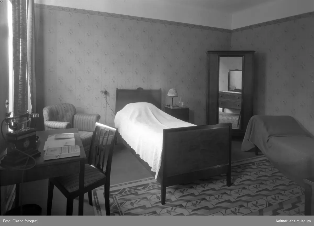 Interiör från sovrum med säng skrivbord och hörnskåp.