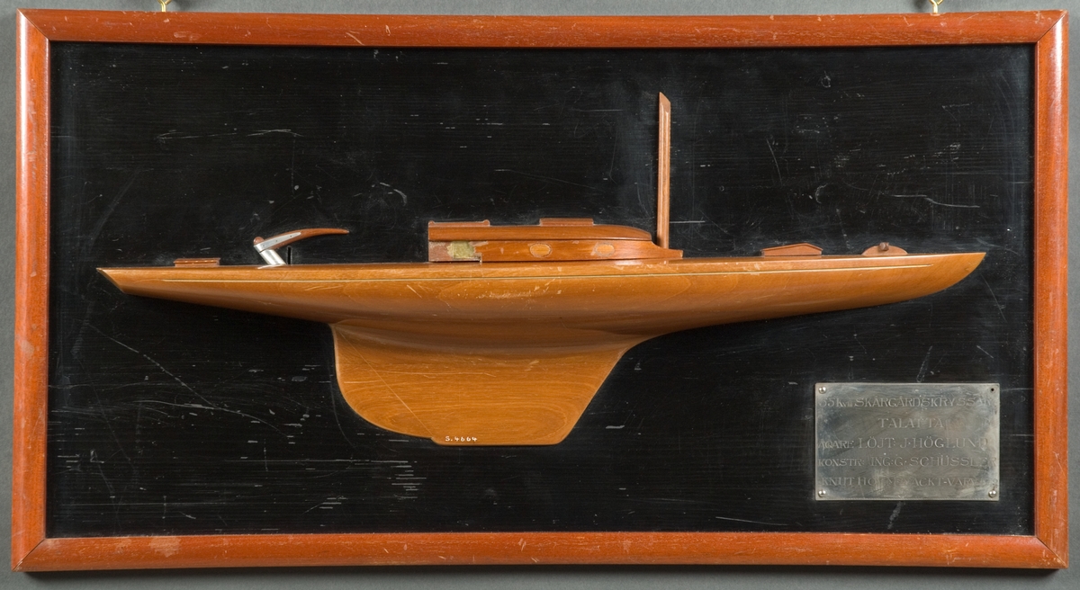 Halvmodell av skärgårdskryssaren TALATTA styrbords sida. En mast, ruff, två kappluckor och rorkult med beslag av vit metall. Skrov av polerat mahogny.Monterat på svart träplatta med brun ram.
