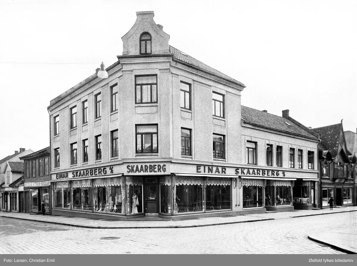 Forretningsgårder i Sarpsborg, St. Mariegate 105.
Einar Skaarberg A/S, manufakturforretning. Skilt "Overretssakfører Mathisen" i 2. etasje.
Til høyre for Skaarberg ser vi btikken til pølsemaker Arnt Bergby, i St. Mariegate 103.