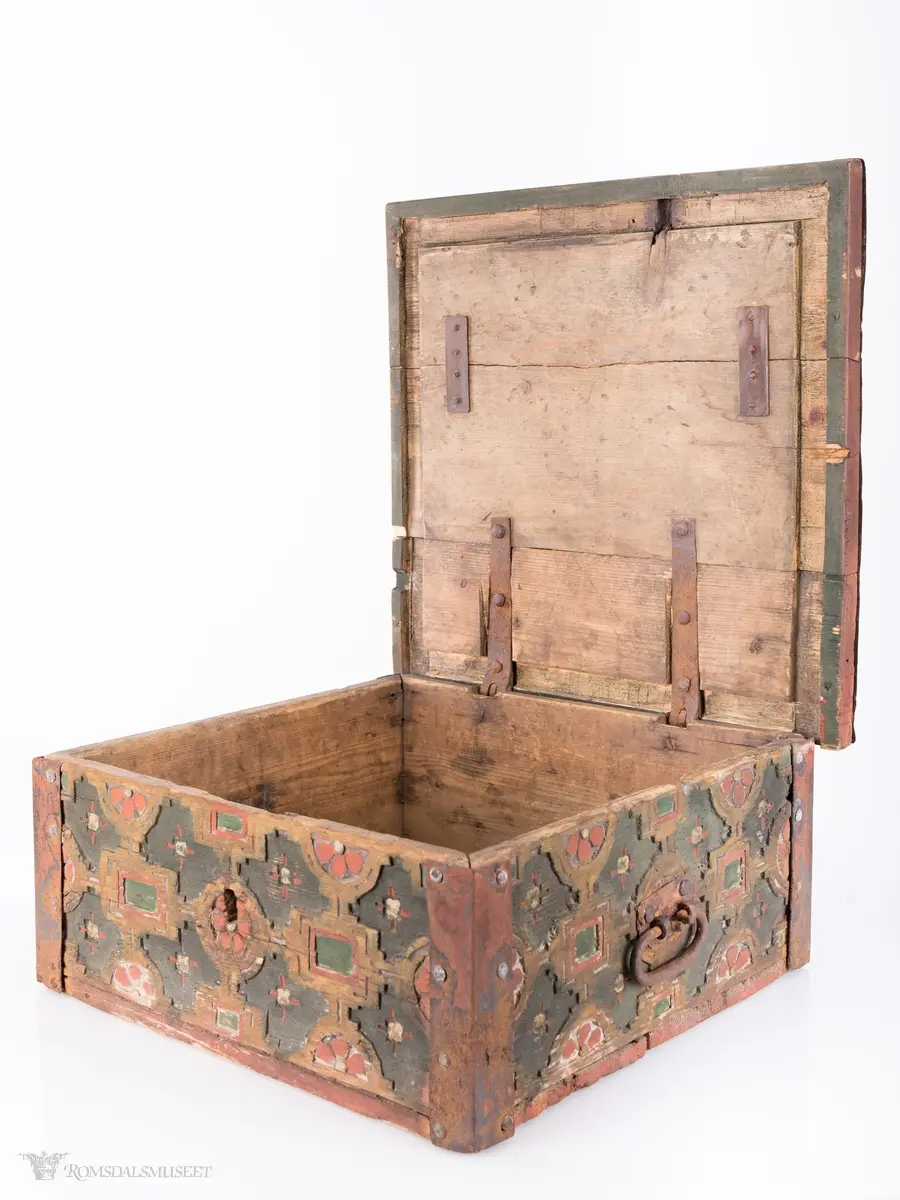 Skårede røde blomster med sirkulær innramming og grønne kvadrater med kvadratisk innramming som går i hverandre og går igjen på lokket. Innemellom disse figurene; små seksbladede hvite blomster med rød knapp. På sidene; grønne rektangler med innramming som går over i de samme røde blomstene med ramme som på lokket, men de fleste grenser mot kantene og blir halvmåneformede.