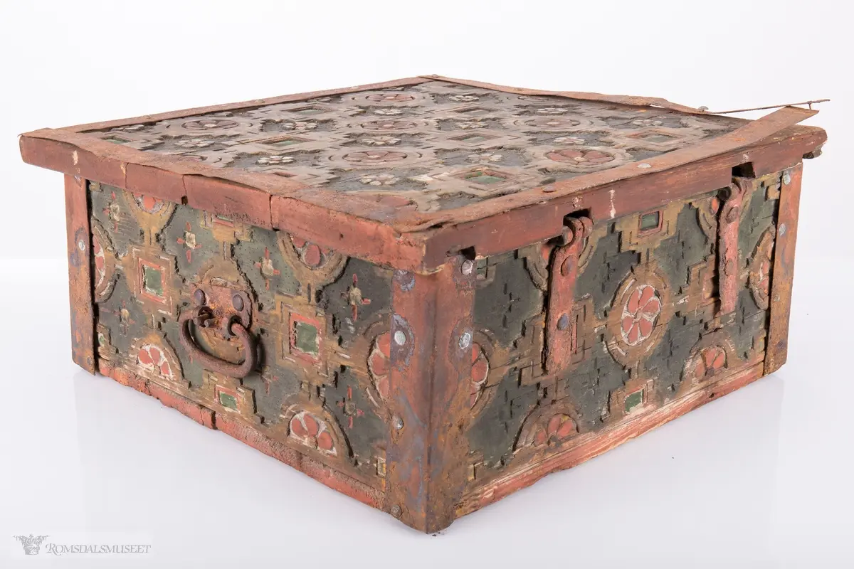 Skårede røde blomster med sirkulær innramming og grønne kvadrater med kvadratisk innramming som går i hverandre og går igjen på lokket. Innemellom disse figurene; små seksbladede hvite blomster med rød knapp. På sidene; grønne rektangler med innramming som går over i de samme røde blomstene med ramme som på lokket, men de fleste grenser mot kantene og blir halvmåneformede.