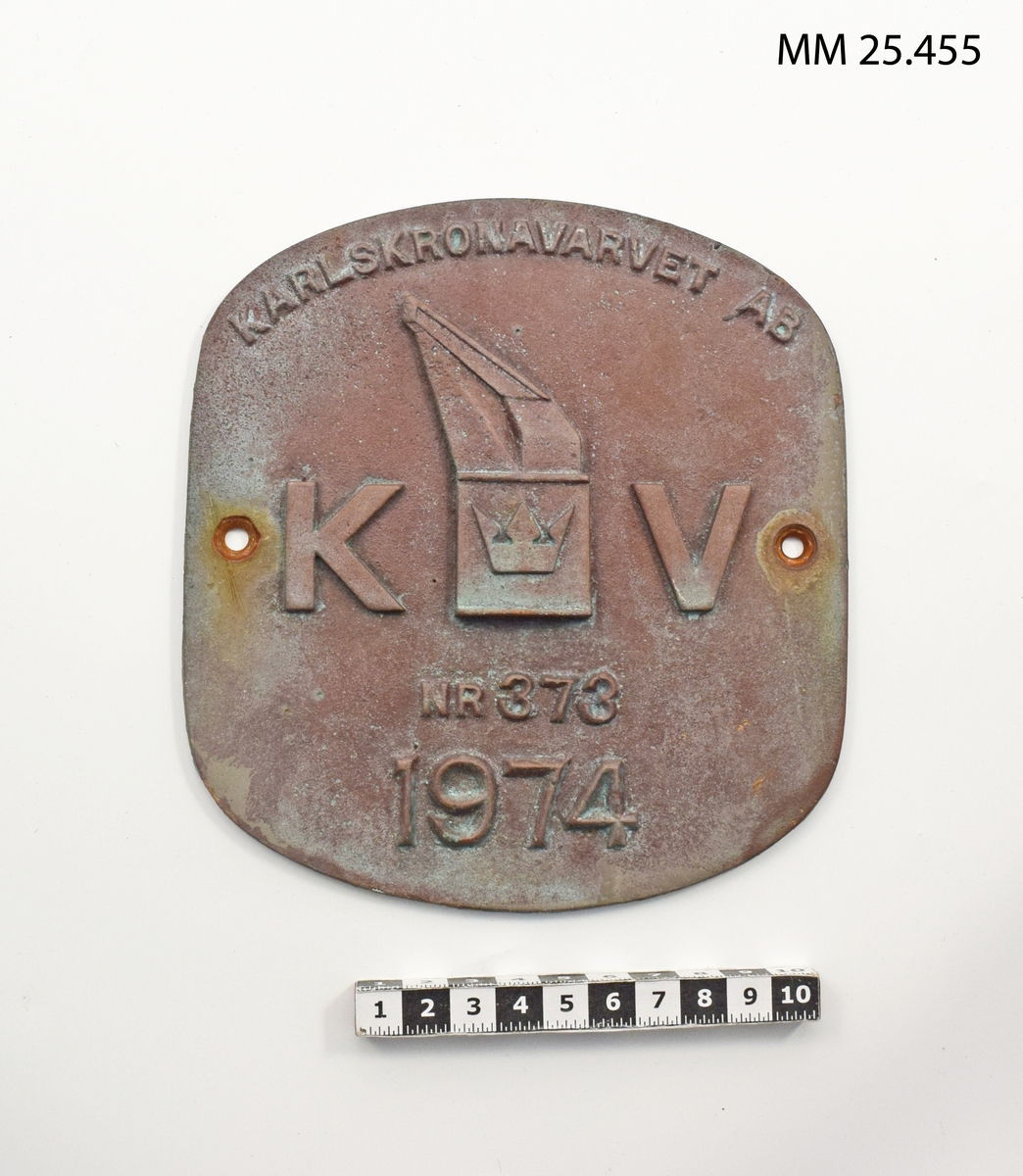 Rektangulär skylt i metall med mjukt rundade kortsidor. På framsidan i relief text : "KARLSKRONAVARVET AB NR 373 1974". Mitt på skylten finns Karlskronavarvets logotype med mastkranen omgärdat av ett K och ett V. På långsidorna borrade hål för montering. 
På baksidan har någon antecknat i tuschpenna: "Rbb Västerås (135) utrangerad 1997-01-01 avr insp 1997-0
4-04 /MJ".
