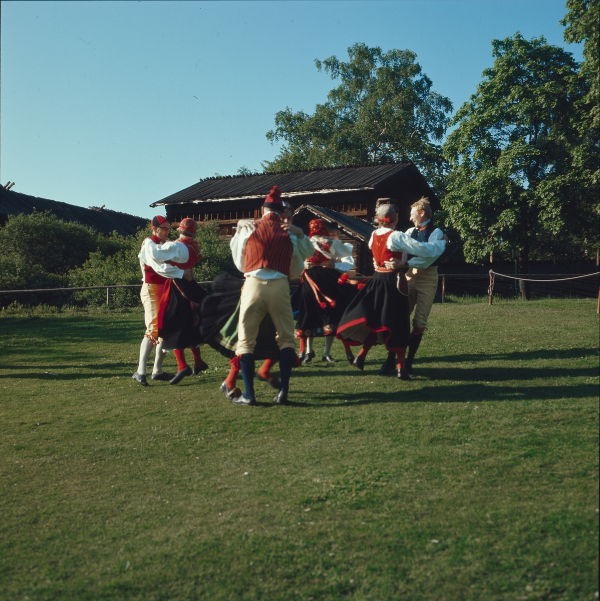 Ett folkdanslag dansar på Orsakullens gräsplan.