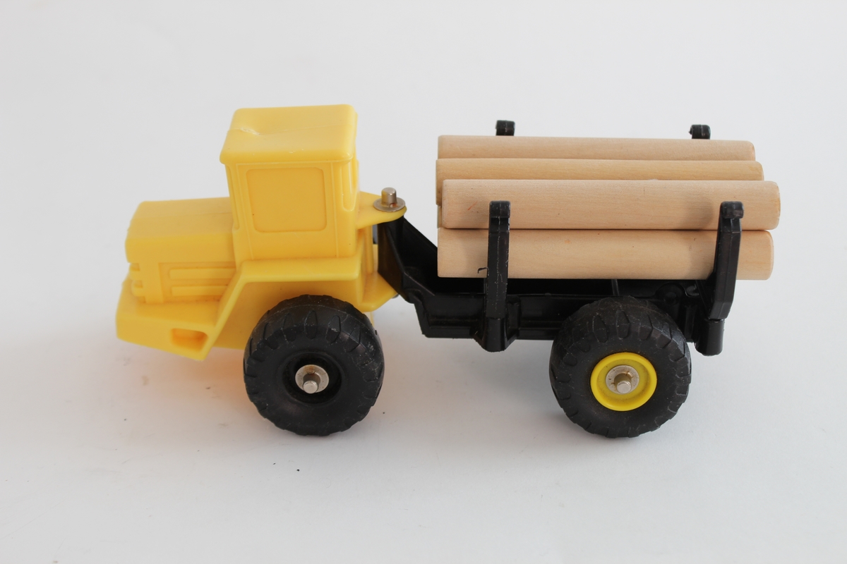 Giver. Bjørn Sverre Hol Haugen (f.1972).
En gul traktor i plastikk, med en svart henger og 6 trepinner som etterligner på tømmer.