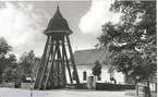 En klockstapel vid en kyrka i nyklassicistisk stil. Karlslunda socken.