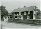 Mangårdsbyggnaden var tidigare en stuga med loft. Verandan har tillkommit vid sekelskiftet 1900. Till vänster om mangårdsbyggnaden syns magasin och drängstuga.