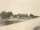 Gården från landsvägen. Närmast ligger de två långa flyglarna i mangården, den ena med handelsbod. Längst bort skymtar ladugården.