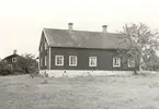 Mangårdsbyggnad. Knuttimrad, klädd med panel av stående bräder med täcklister, tak av enkupigt tegel. Rödmålad med vita knutar, dörr- och fönsterfoder.