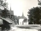 Voxtorps kyrka med klockstapel. Bodar i förgrunden.