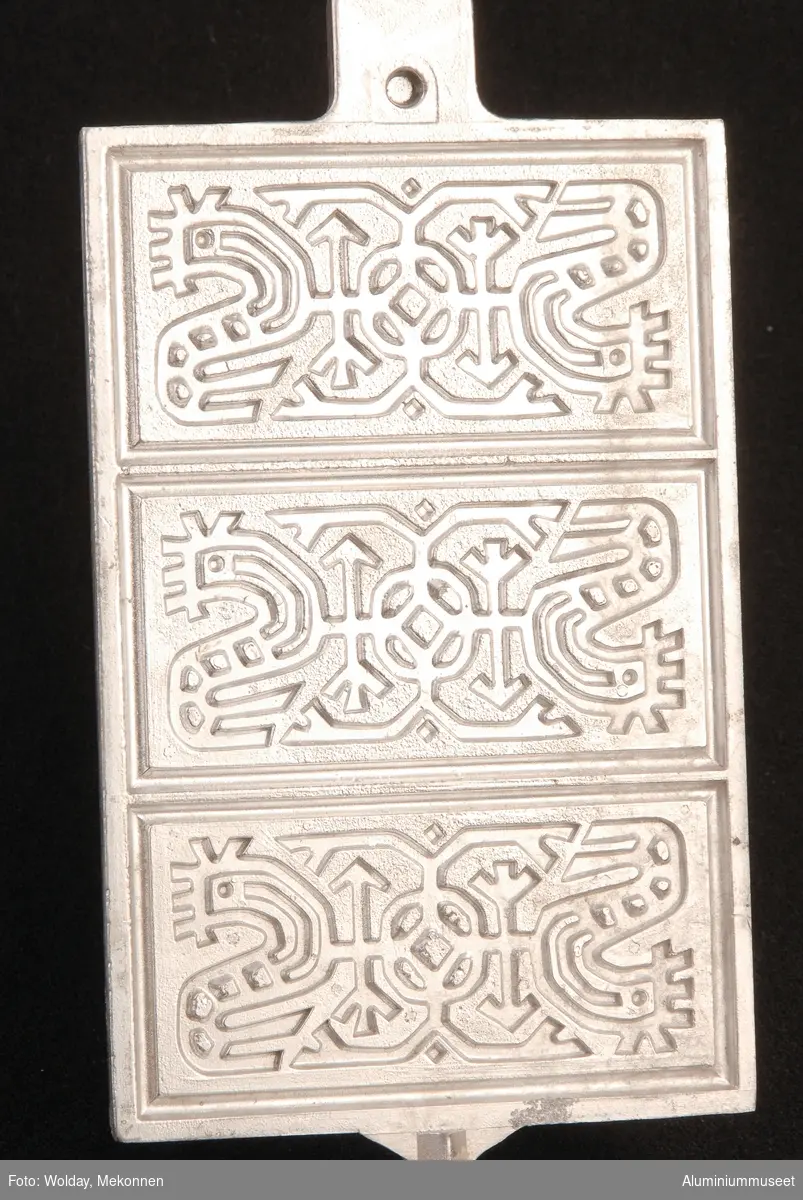 Teknikk: Pannen er kokillestøpt i to halvdeler, en overdel og en underdel. Håndtakene er innlagt i kokillene og er støpt fast. Delene ble plandreid, men dreiing er ikke utført på dette eksemplaret. Naglehullet er boret og naglen er klinket for hånd.
Form: Vanlig flat panneform
