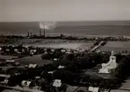 Flygfoto över Degerhamns cementfabrik, som senare kom att ingå i Cementakoncernen, samt samhället med hus, kyrka och åkermark mot Kalmarsund.