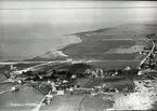 Flygfoto över Grönhögen. Byn med byggnader, cementfabrik och hamn.