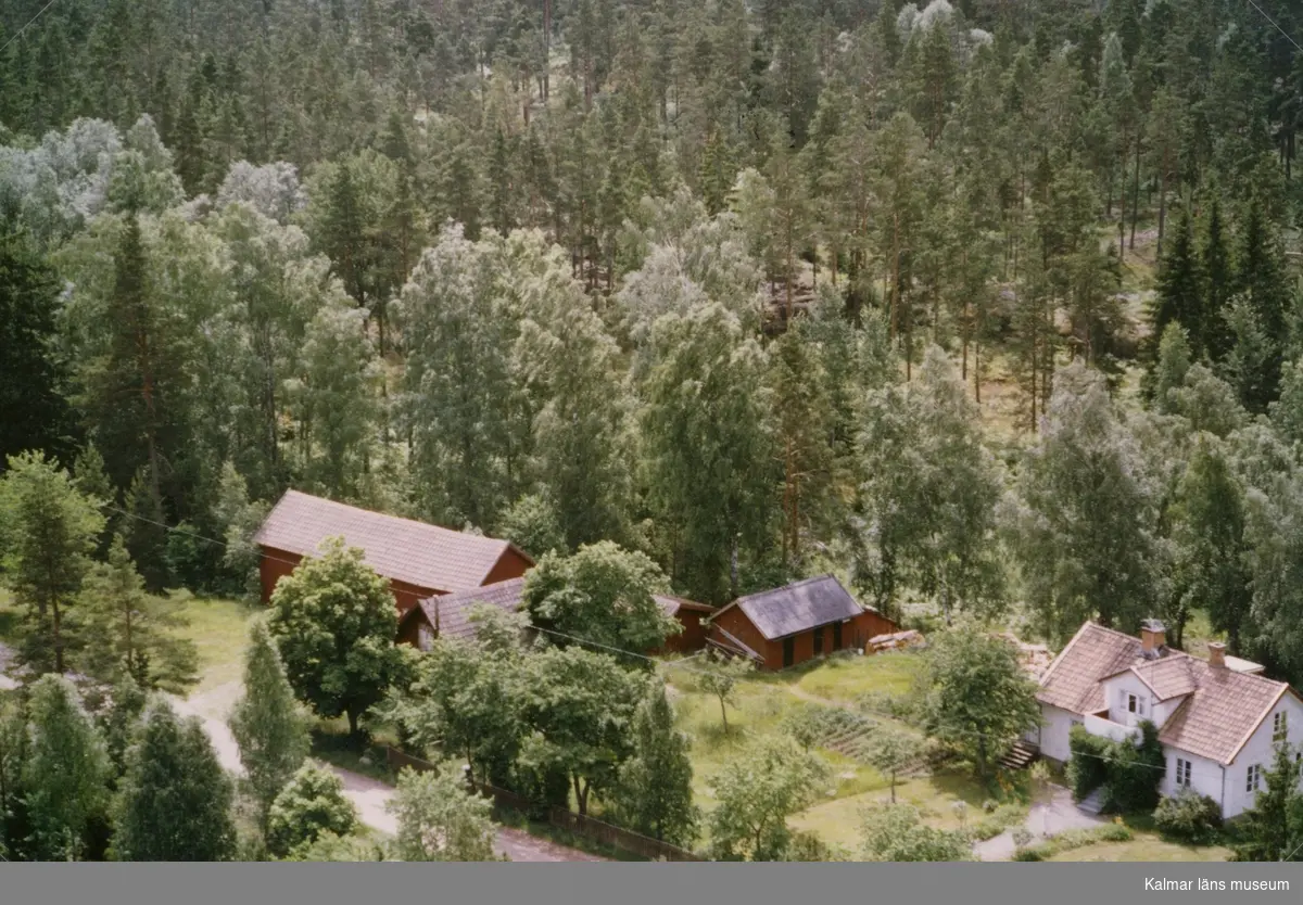 En gårdsmiljö, omgiven av skog, i Döderhult.