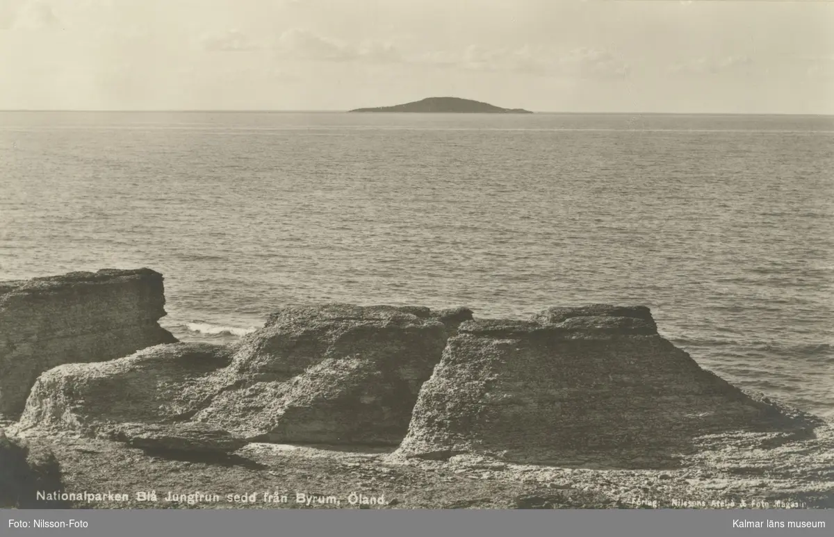 Blå Jungfrun sedd från Byrum, Öland.

"Nationalparken Blå Jungfrun sedd från Byrum, Öland.

Förlag:Nilssons Ateljé och Fotomagasin, Borgholm."