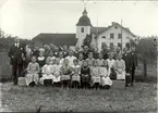 Klassfoto av årskurserna 3 och fyra framför kyrkan och skolan i Hjorted.