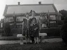 Kvinna och två barn framför ett bostadshus i Widebergs trädgård.