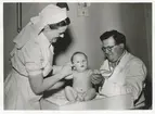 Dr Erik Linde och hans sköterska undersöker en bebis.