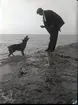 En man och en hund vid en klippstrand.