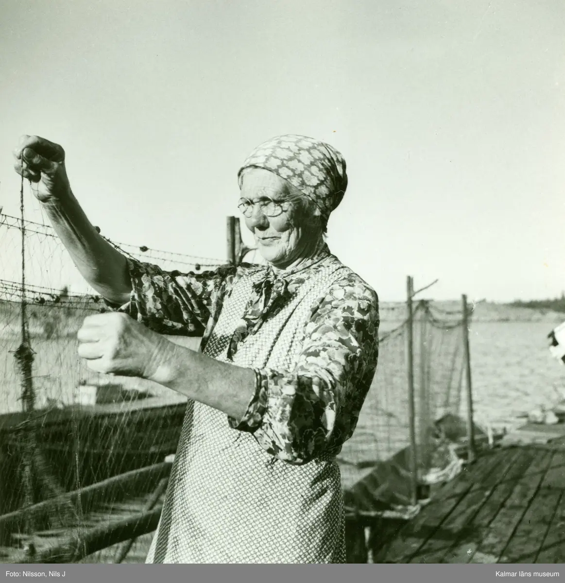 Anna Svensson, änka, hänger flundregarn till tork.