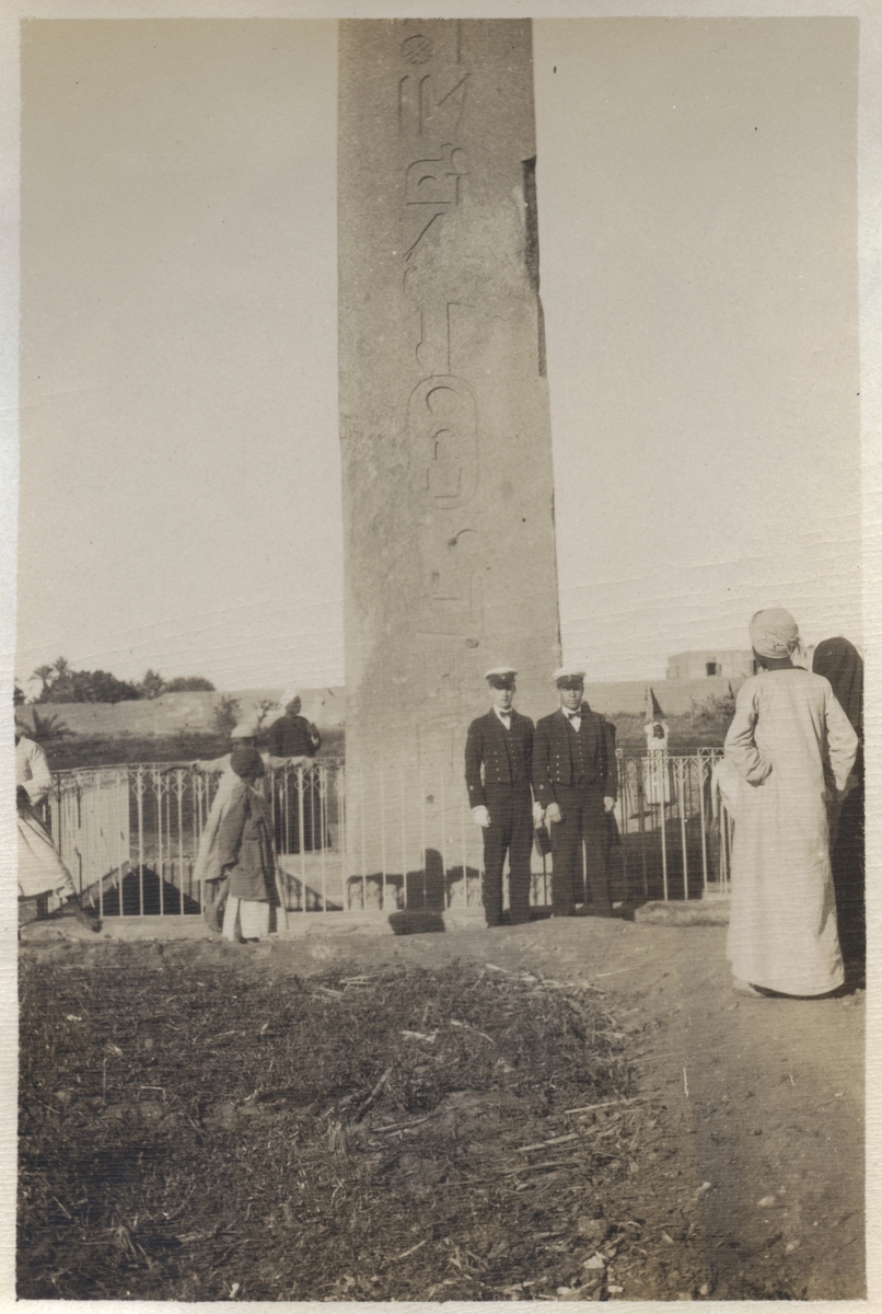 Två svenska sjöofficerare poserar intill oidentifierad obelisk, sannolikt i arabland. Officeren till höger är Gunvald Berger, till vars samling bilden hör. Berger deltog 1925-1926 i pansarkryssaren FYLGIAs långresa till bl a Alexandria och Tunis och 1927 då fartyget seglade till Medelhavet, därvid angjordes bl a Alger.