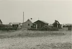 En gård i Klockholm. Några bodar och bostadshus i träfasad.