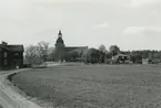 Törnsfalls kyrka i Bakgrunden. Åkerlandskap i förgrunden.