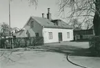 Ett bostadshus med putsad fasad och en häck på Baggensgatan 1 i Ängö.