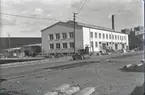 Fabriksbyggnad på industriområdet med spårområde i förgrunden.