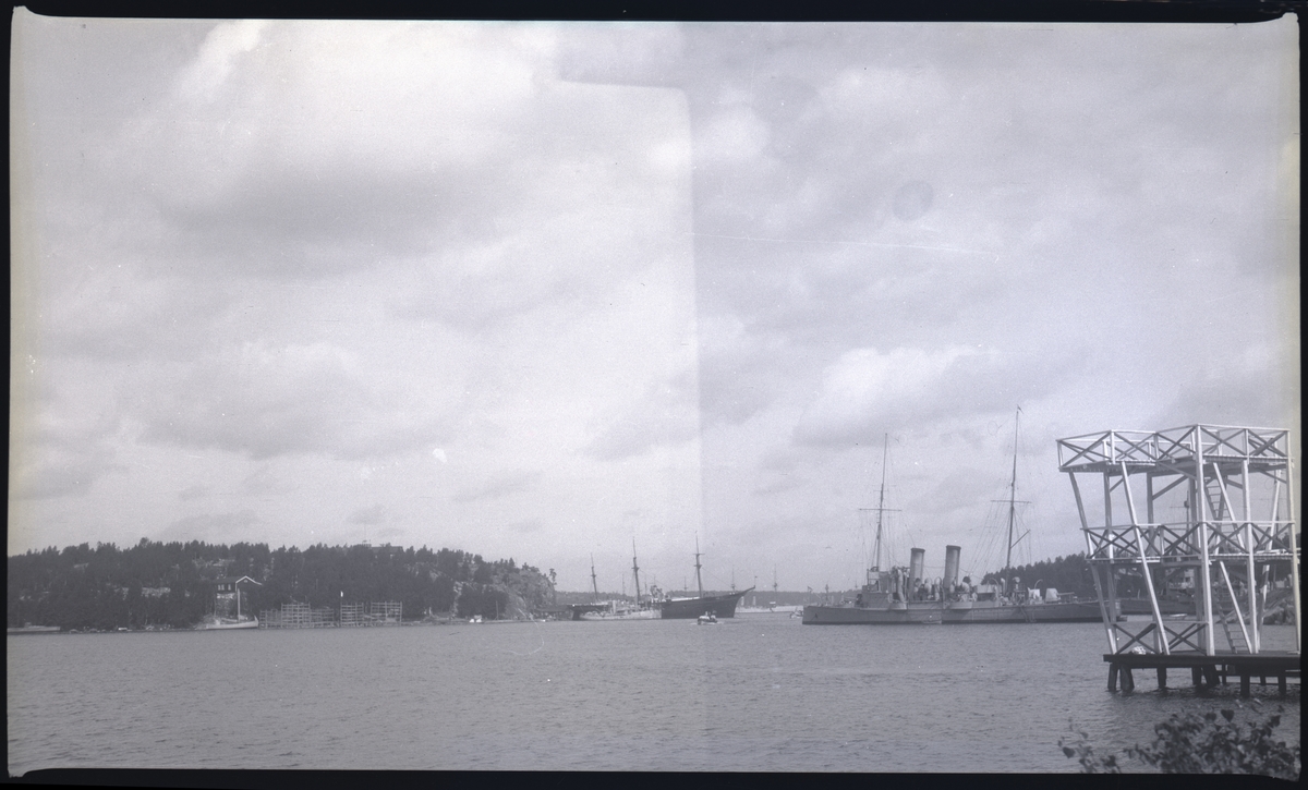 Från Hårsfjärdens marinbas, Märsgarn till v, Vitsgarn till h. Om bilden likt de flesta i Bergers samling tagits vid slutet av 1920-talet bör fartyget till h vara torpedkryssaren PSILANDER, som då var skolfartyg. I mitten oidentifierat segelfartyg med mindre fartyg framför. Till v vad som förefaller vara en fiskebåt.