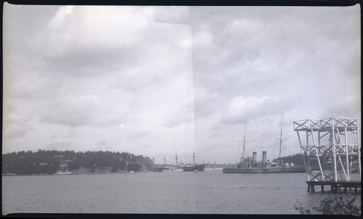 Från Hårsfjärdens marinbas, Märsgarn till v, Vitsgarn till h. Om bilden likt de flesta i Bergers samling tagits vid slutet av 1920-talet bör fartyget till h vara torpedkryssaren PSILANDER, som då var skolfartyg. I mitten oidentifierat segelfartyg med mindre fartyg framför. Till v vad som förefaller vara en fiskebåt.