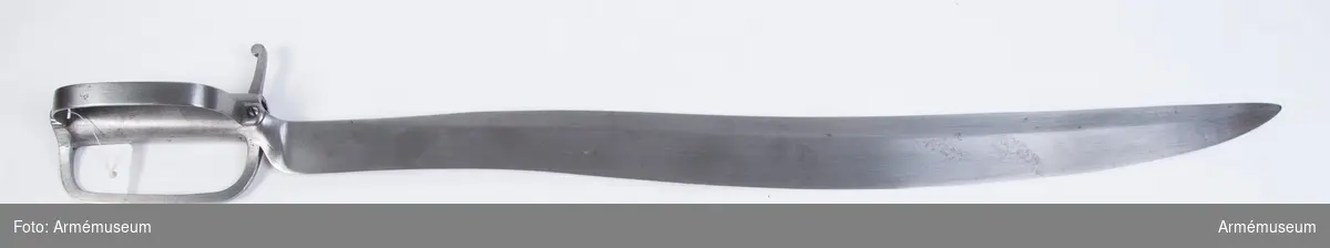 Klingans största bredd är 50 mm (250 mm ovanför udden).
Vapnet är likt AM 36648 (tidnr. 5137), utom att klingan är något kortare, samt att fästet på yttersidan har en bugel som går från korset tiil kavelns övre ände. På det förstnämda stället, fasthålles den av skruv, på den sistnämnda av en nit.