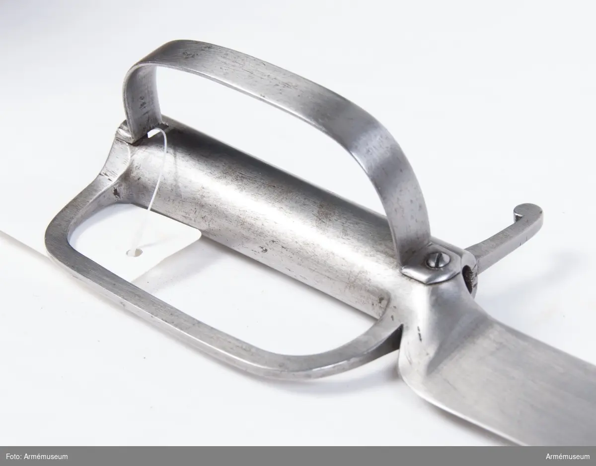 Klingans största bredd är 50 mm (250 mm ovanför udden).
Vapnet är likt AM 36648 (tidnr. 5137), utom att klingan är något kortare, samt att fästet på yttersidan har en bugel som går från korset tiil kavelns övre ände. På det förstnämda stället, fasthålles den av skruv, på den sistnämnda av en nit.