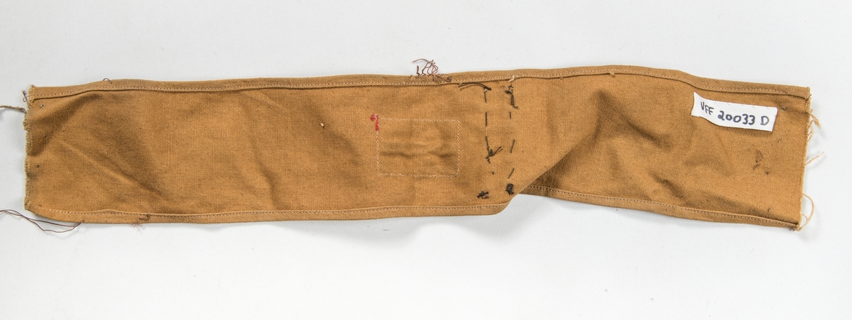 Militæruniform, Jakke (A) i grønt ulltøy. Liggane krage, stolpe i opninga med fem knappehol og fem knappar. Linning nederst med metallspenne. Ei utanpålomme på kvar side med knapp og knappehol. Skulderklaffar. Saum midt bak. Erme med mansjett, knapp og knappehol.
Bukse (B) i same tøy. Linning og gylf med knappar.  To stikklommer, to utanpåsydde lommer på framsida, og ei baklomme.
Armband (C) i gråbrunt med påsydd norsk flagg, to svarte sikkerheitsnåler (var festa til jakka).
Armband (D) i lys brunt med påsydd norsk flagg og to raude stipe (var festa til jakka).
Band (E) Smalt tjukt band (belte) med avrunda metalavslutning i endene. Spenne i eine enden og knapp i den andre.
(C D E ligg i eske i fag III, hylle 2b)