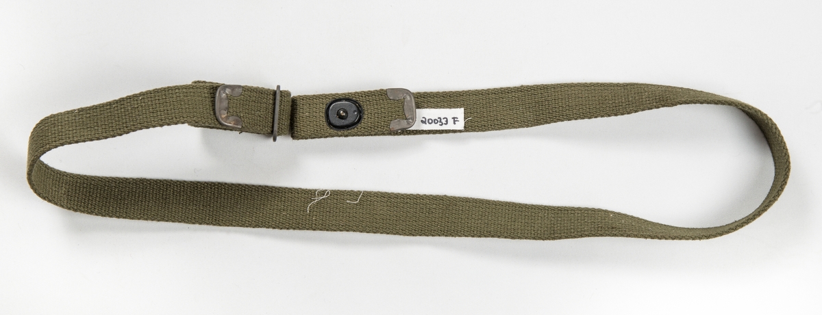 Militæruniform, Jakke (A) i grønt ulltøy. Liggane krage, stolpe i opninga med fem knappehol og fem knappar. Linning nederst med metallspenne. Ei utanpålomme på kvar side med knapp og knappehol. Skulderklaffar. Saum midt bak. Erme med mansjett, knapp og knappehol.
Bukse (B) i same tøy. Linning og gylf med knappar.  To stikklommer, to utanpåsydde lommer på framsida, og ei baklomme.
Armband (C) i gråbrunt med påsydd norsk flagg, to svarte sikkerheitsnåler (var festa til jakka).
Armband (D) i lys brunt med påsydd norsk flagg og to raude stipe (var festa til jakka).
Band (E) Smalt tjukt band (belte) med avrunda metalavslutning i endene. Spenne i eine enden og knapp i den andre.
(C D E ligg i eske i fag III, hylle 2b)