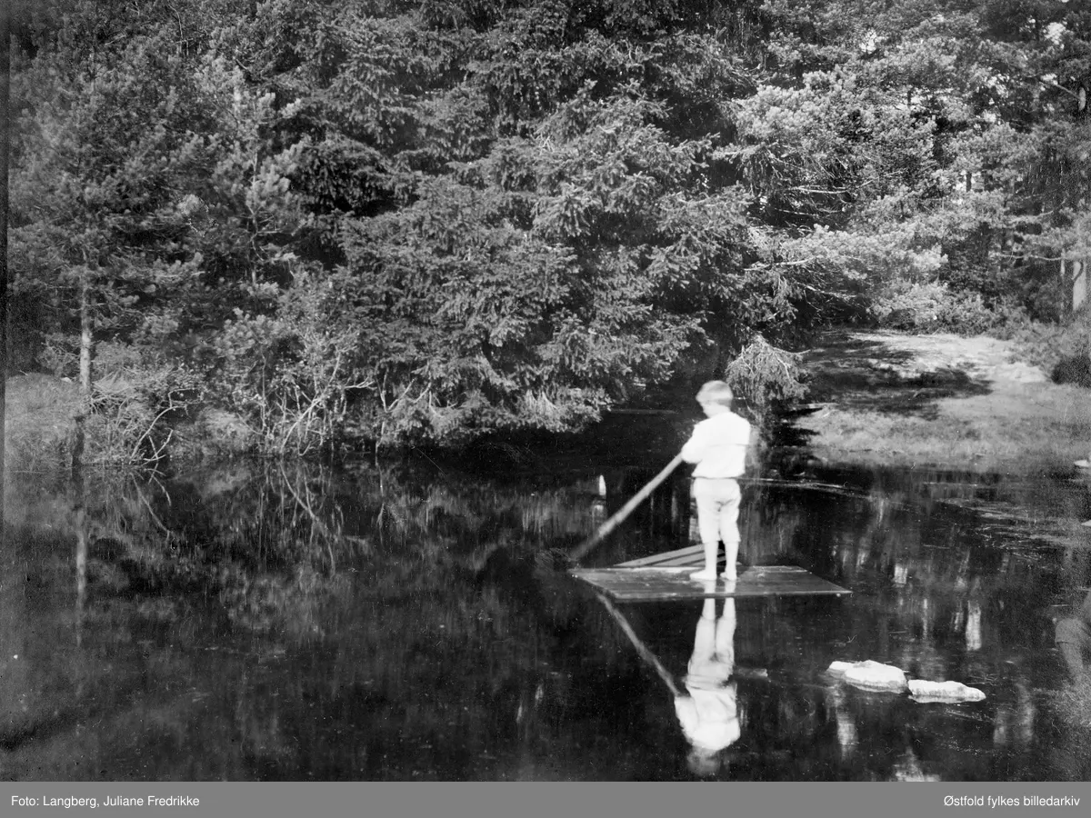 Christoffer Lorentz Holm (f. 1892) på flåten på dammen bak husene på Bergenhus kapellangård i Rakkestad ca. 1897. Gutten var sønn av Louise Langberg (f. 1853) og prest Olaf Andreas Holm( f. 1845). Han er fotografert av sin mors søster.
Som voksen arbeidet han som forvalter ved Rosendal baroni.