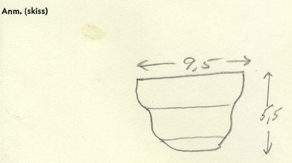 Arkitektoniskt ornament i form av en sockel till en kolonn. Ett spikhål (som dock täcks av taggen), vertikal fals på baksidan. Baksida samt fals välbevarade, i övrigt kraftigt vittrad. Profilering ej längre urskiljbar. Ingen saltskada.