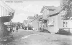 Gatubild från Rödesund, Storgatan med den gamla bebyggelsen. Till vänster syns sista marknadsboden som revs år 1904. På bilden har Fallanders hus försetts med veranda. Förstoring 31 x 50 cm. Neg finns.