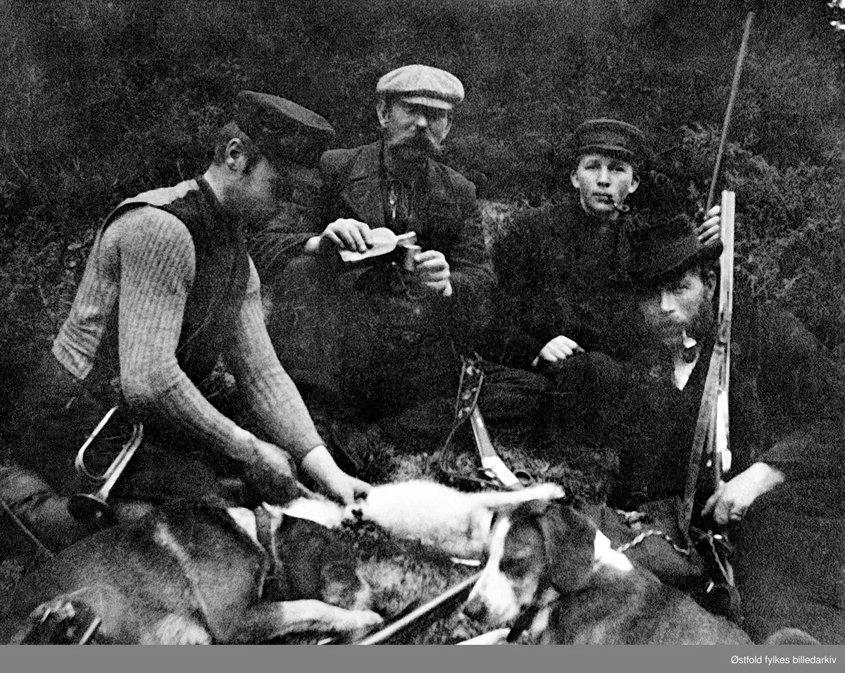 Harejakt i Lundebyskogen ca. 1902-03.
Fra venstre: Willas Lundeby (F.1879), Hans Engebrethsen(F.1856) Georg Lundeby (F.1882), Fredrik Friis Giebelhausen, fotograf Fredrikstad. De to førstnevnte var gårdbrukere. naboer på jakt, ant i Lundebyskogen. Se også ØFB.1989-00116.