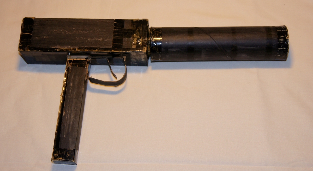 Falskt våpen i sortmalt papp som skal ligne en Uzi maskinpistol.