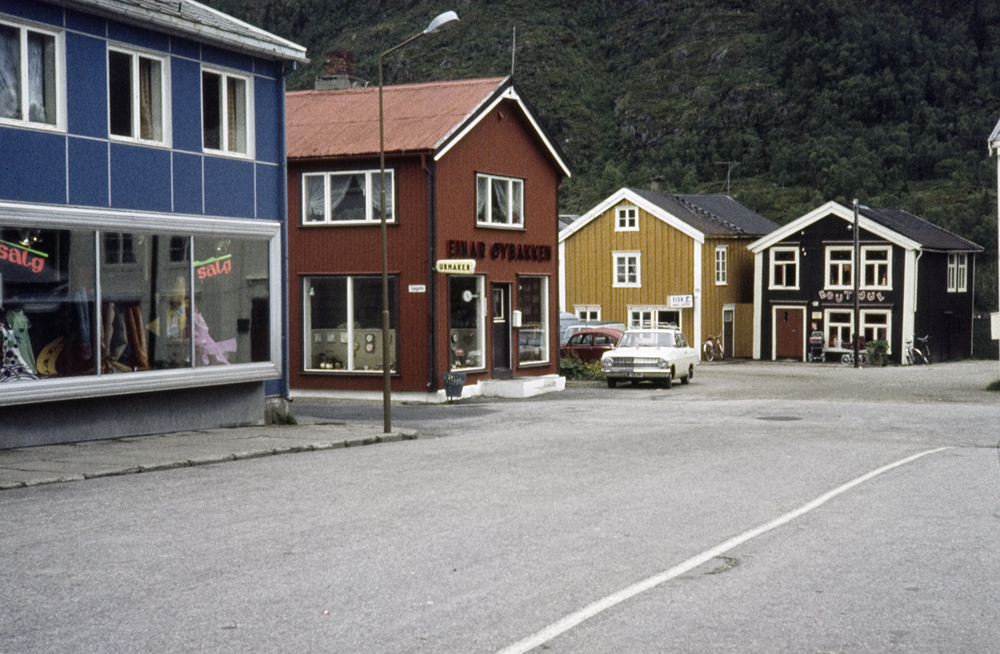 Torget i Mosjøen mot Sjøgata. Fra venstre: Baadstøhuset, Urmaker Einar Øybakken, Juviks Fiskeforretning (25d) og Baadstøbrygga (25c)