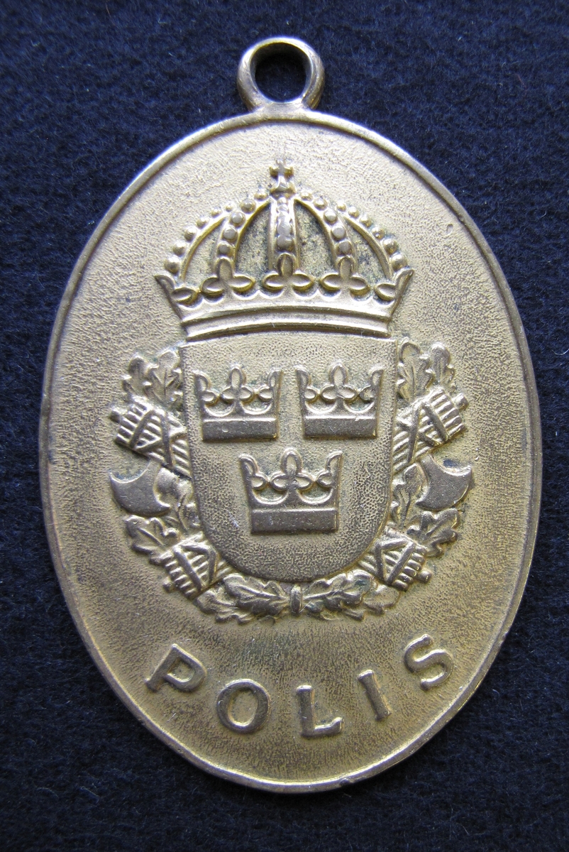 Polisbricka, oval med en ögla i toppen. 

På framsidan: Lilla riksvapnet, dvs en krönt sköld med tre kronor. Bakom skölden eklöv och korslagda fasciner. Under emblemet står det POLIS

På frånsidan: STATSPOLISEN står den i det övre kanten. Mitt på står NR. 1706. Även tillverkaren Sporrong & CO, Stockholm finns ingraverat.