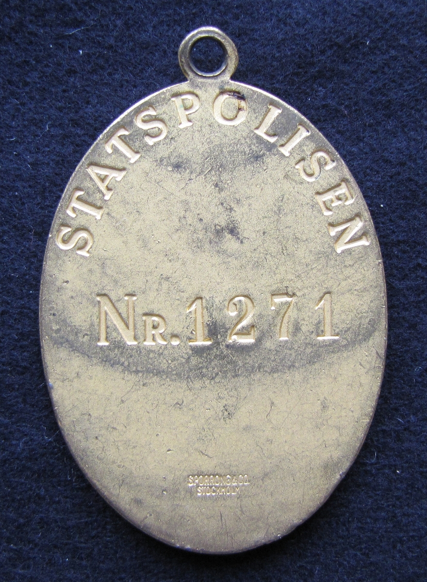 Polisbricka, oval med en ögla i toppen. 

På framsidan: Lilla riksvapnet, dvs en krönt sköld med tre kronor. Bakom skölden eklöv och korslagda fasciner. Under emblemet står det POLIS.

På frånsidan: STATSPOLISEN står den i det övre kanten. Mitt på står NR. 1271. Även tillverkaren Sporrong & CO, Stockholm finns ingraverat.