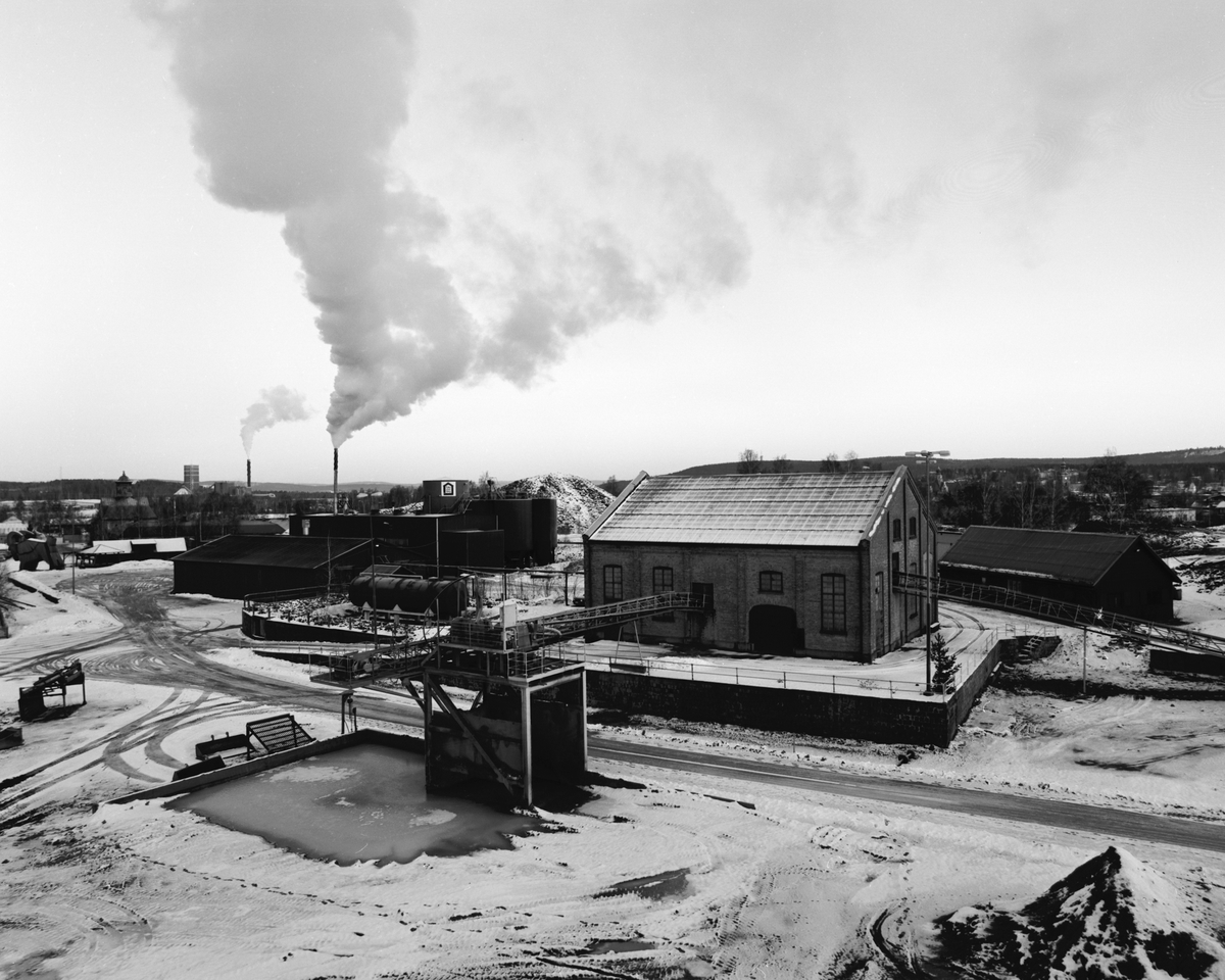 Dokumentation av Falu rödfärg.
Bilden tagen uppifrån en av råvaruhögarna, i förgrunden tegelbyggnaden och slammeriet, byggt 1925. I bakgrunden "hyttan" som köres för fullt enligt röken från skorstenen.