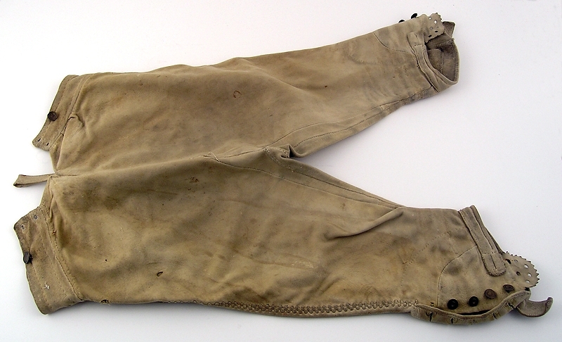 Ett par knäbyxor av ljust skinn.
Sprund vid knät, knäppning med fyra metallknappar.
Knäppning med lucka fram, sex tränsade knapphål.
Sprund mitt bak med tränsade hål för snörning av midjevidd.
Linning, överdel lucka samt del av knäsprund är fodrade med grovt linne.

Gåva till Husaby hembygdsförening av Adolf Svahn som köpt byxorna på auktion efter Petter Larssons barnbarn Erland Johansson, Skattegården, Husaby ( f 1852).

Se bilaga till liggare