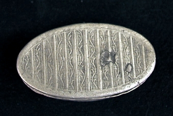 Oval snusdosa. På locket två medaljonger med kvinnobyster, sidorna och botten ornerade med omväxlande stolpar och rankor.