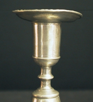 Ljusstake med stor, rund fotplatta. Pärlstav omkring fotplattan och ljusmanschetten.