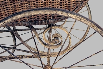 Barnvagn av korg, dvs flätad pil. Smalt profilsvarvat handtag. Insidan klädd med blåvitt, blommigt bomullstyg. Gulmålat stålunderrede med svarta ränder. 4 mycket stora hjul med ekrar, de bakre allra störst, i samma färger.
Använd vid barnens dagsfirande i Skara av släpvagnen Erik Sjöstrand, enligt äldre katalog.


Neg.nr: 82/439/10
Sakord: BARNVAGN
Tillverkningstid: 1900-1920
Material: PIL STÅL BOMULL
Teknik: FLÄTAT GJUTET SMITT
Mått: L=1070 B=490 H=900
Vikt: